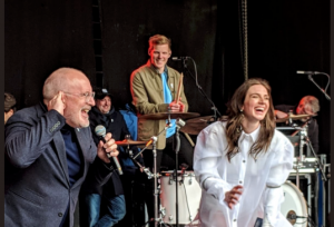 foto van Frans Timmermans op het podium van het Bevrijdingsfestival in Assen. Rechts: zangers Maan.
